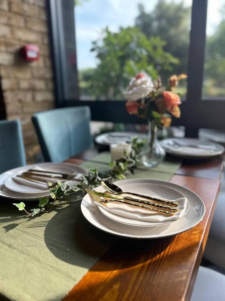 A long table laid with gold cutlery and greenery, looking out towards Brockwell Park